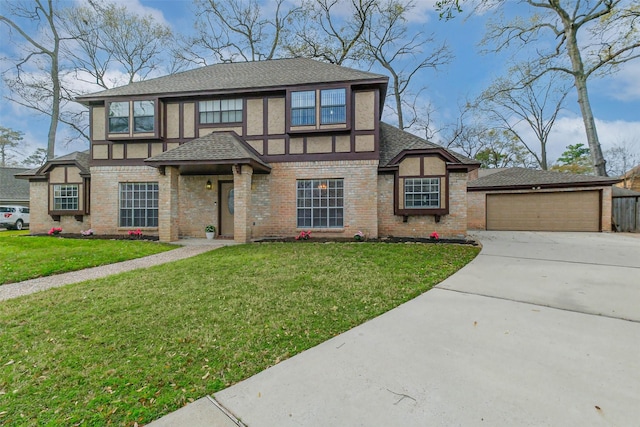 english style home featuring brick siding, a shingled roof, a front yard, a garage, and driveway