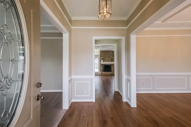 foyer entrance featuring a wainscoted wall, wood finished floors, an inviting chandelier, and ornamental molding