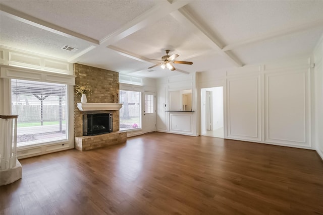 unfurnished living room with a brick fireplace, a decorative wall, visible vents, and coffered ceiling