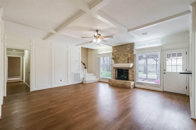 unfurnished living room featuring a decorative wall, a fireplace, coffered ceiling, and wood finished floors