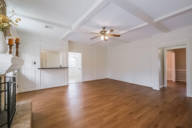 unfurnished living room with a brick fireplace, a decorative wall, wood finished floors, and visible vents