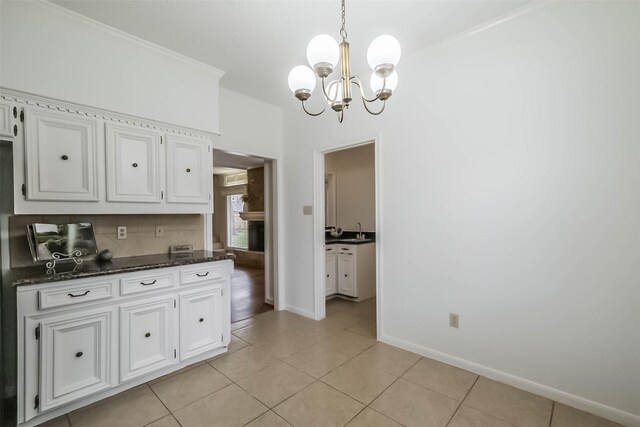 kitchen featuring light tile patterned flooring, white cabinetry, tasteful backsplash, and ornamental molding