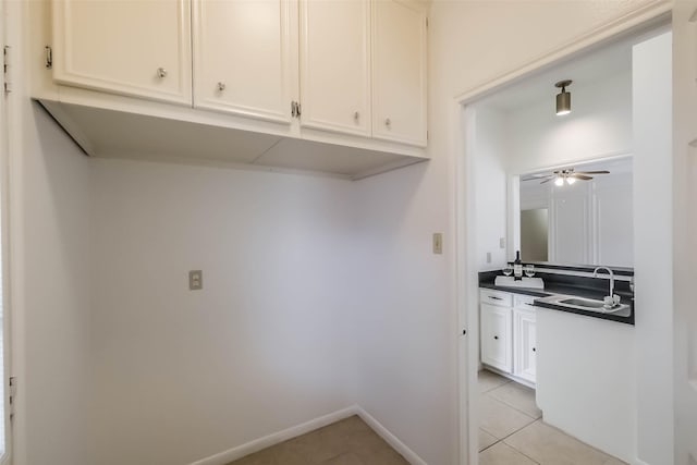 laundry area featuring light tile patterned flooring, a ceiling fan, baseboards, and a sink