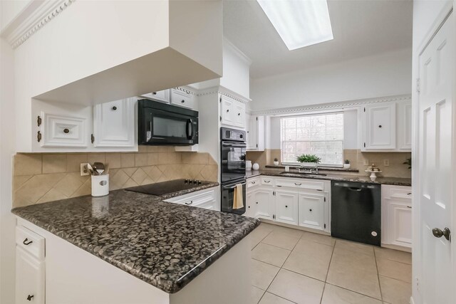 kitchen with a sink, black appliances, white cabinets, and light tile patterned floors