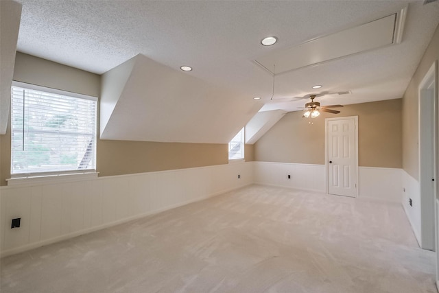 bonus room featuring attic access, carpet flooring, a healthy amount of sunlight, and a wainscoted wall