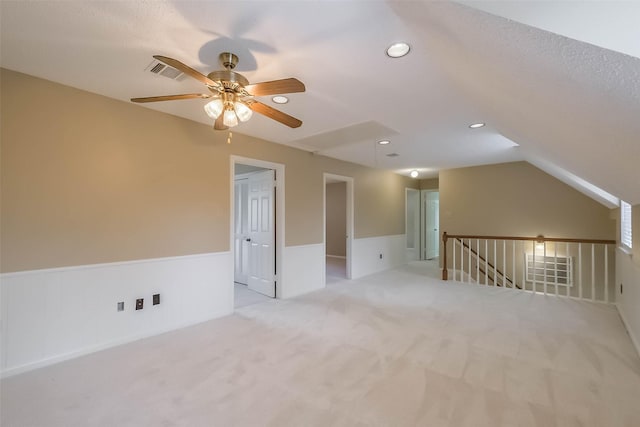 additional living space featuring visible vents, carpet, a wainscoted wall, vaulted ceiling, and recessed lighting