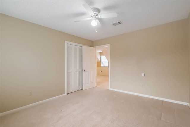 unfurnished bedroom with a closet, baseboards, light colored carpet, and visible vents