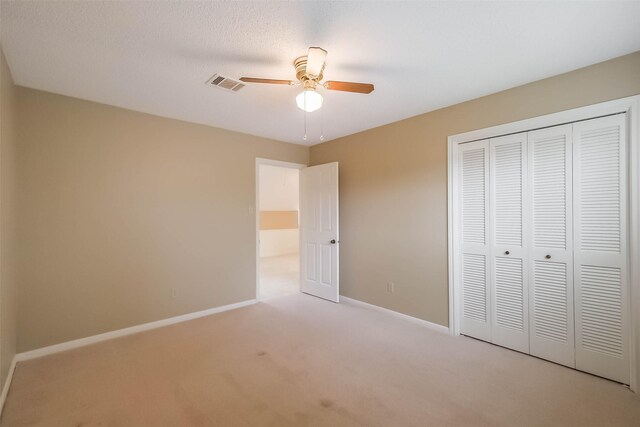 unfurnished bedroom featuring visible vents, carpet, baseboards, a closet, and a ceiling fan