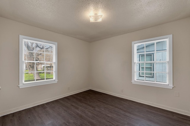 spare room with dark wood-style floors, a textured ceiling, and baseboards