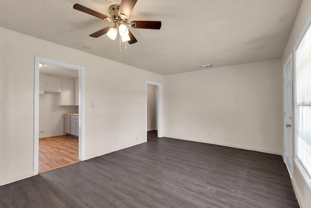 empty room with dark wood-style floors, a textured ceiling, and baseboards