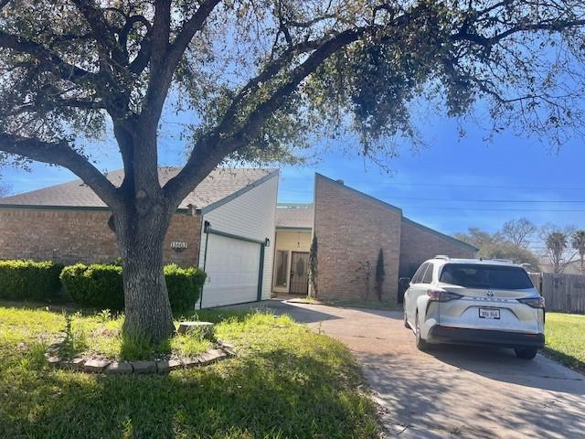 view of front of home with a garage, brick siding, concrete driveway, and fence