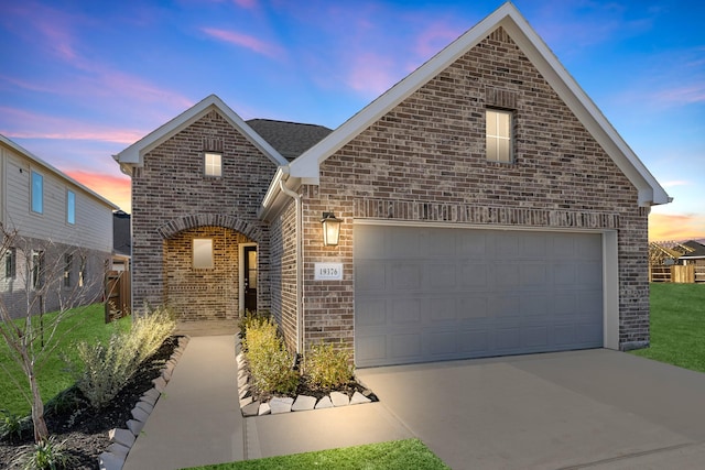 view of front of home with brick siding, a lawn, concrete driveway, and a garage