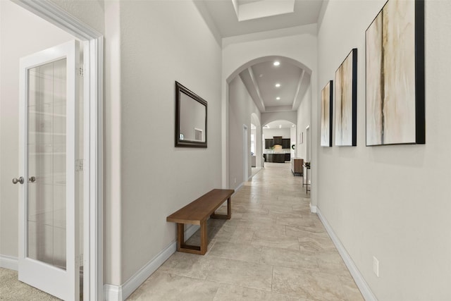 hallway with recessed lighting, baseboards, and arched walkways