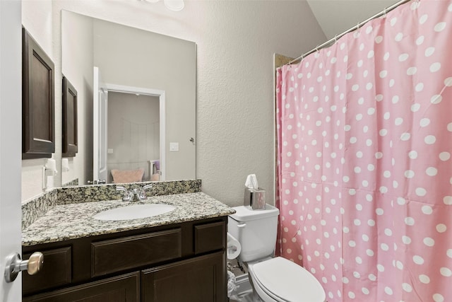 bathroom featuring a shower with curtain, toilet, vanity, and a textured wall