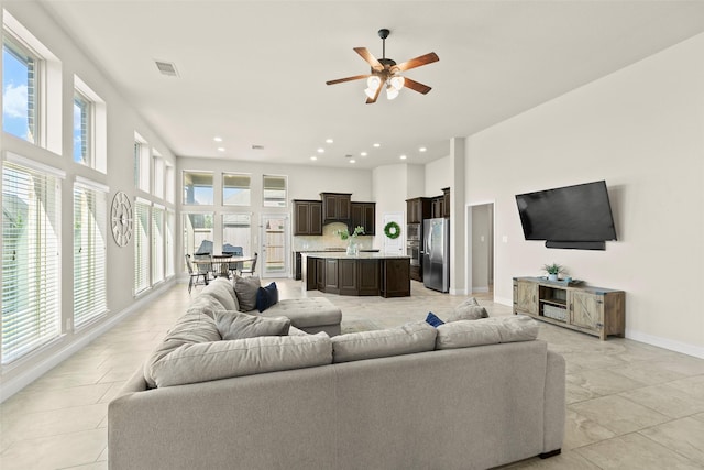 living area with a high ceiling, recessed lighting, baseboards, and a wealth of natural light