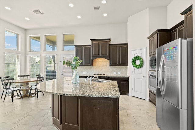 kitchen featuring a high ceiling, backsplash, visible vents, and appliances with stainless steel finishes