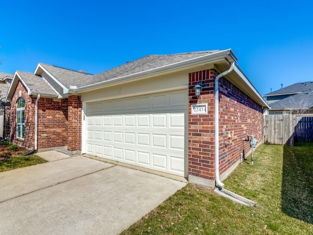 view of home's exterior featuring brick siding, fence, a lawn, a garage, and driveway