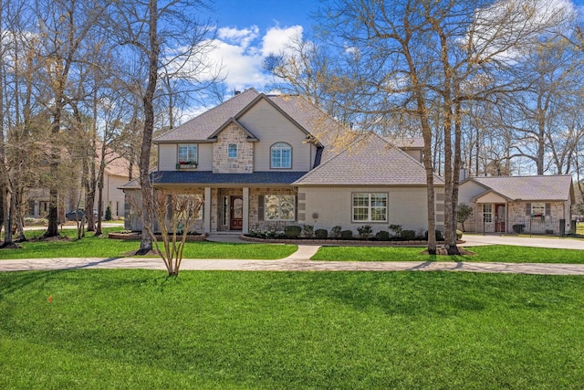 view of front of home featuring stone siding, roof with shingles, covered porch, and a front yard