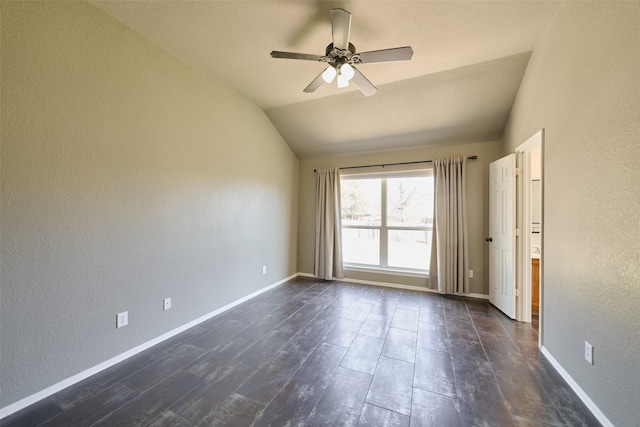 unfurnished room featuring a ceiling fan, dark wood-style floors, baseboards, vaulted ceiling, and a textured wall