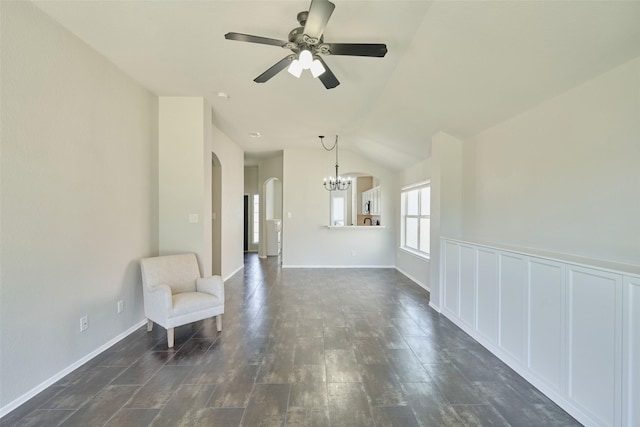 unfurnished room featuring dark wood-style floors, baseboards, lofted ceiling, arched walkways, and ceiling fan with notable chandelier