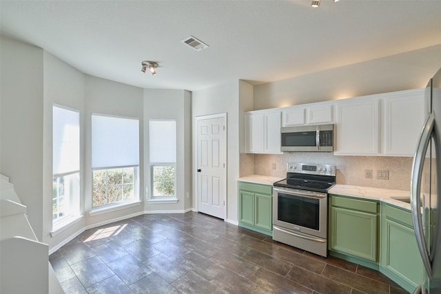 kitchen featuring green cabinets, backsplash, visible vents, and appliances with stainless steel finishes