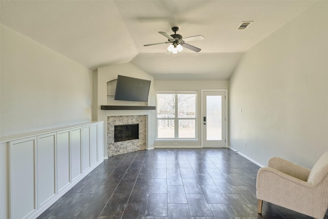 unfurnished living room featuring visible vents, baseboards, lofted ceiling, a fireplace, and a ceiling fan