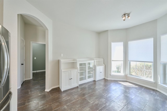 empty room with arched walkways and baseboards