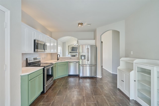 kitchen with green cabinets, decorative backsplash, stainless steel appliances, white cabinetry, and a sink