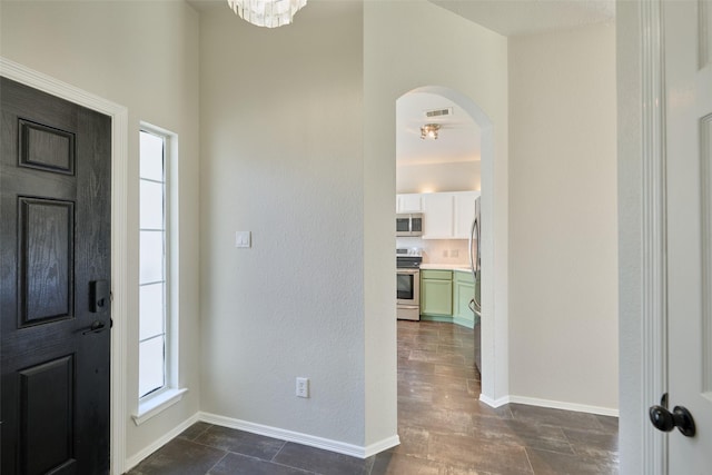 foyer entrance featuring visible vents, baseboards, and arched walkways