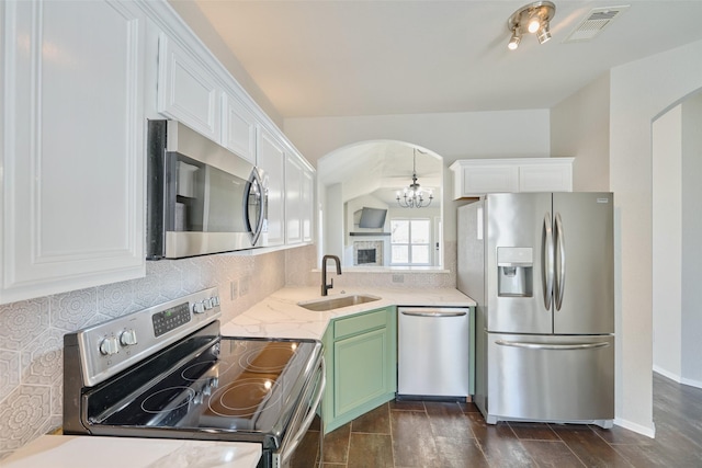 kitchen with white cabinetry, arched walkways, appliances with stainless steel finishes, and a sink