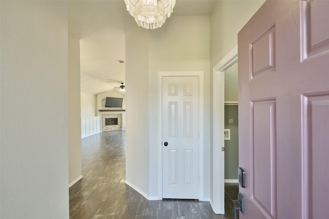 hall with dark wood finished floors, lofted ceiling, a notable chandelier, and baseboards