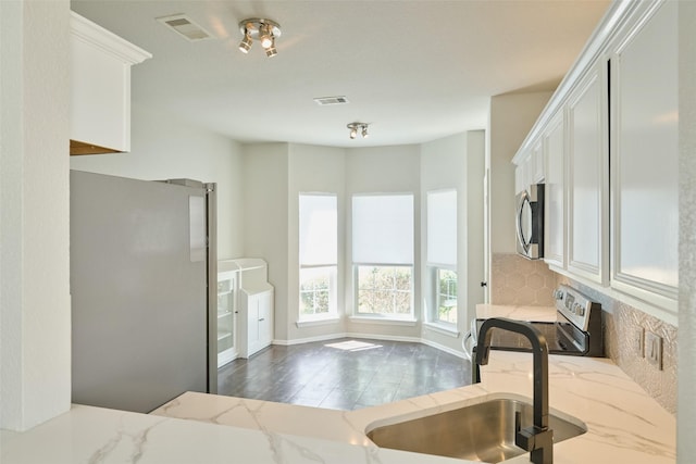 kitchen with light stone counters, visible vents, backsplash, and stainless steel appliances