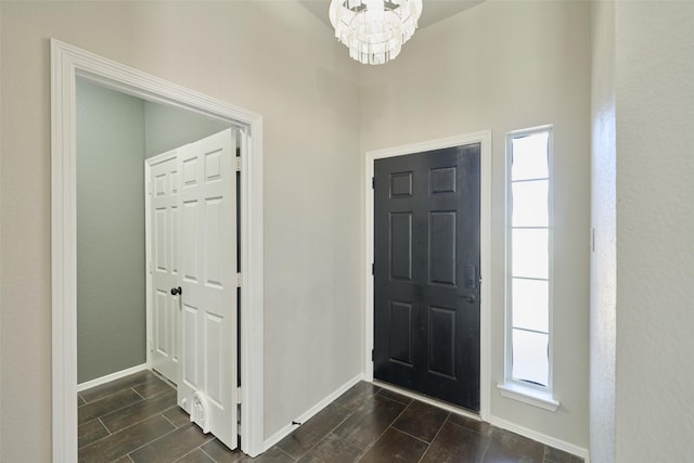 foyer entrance with a wealth of natural light, a chandelier, baseboards, and wood finish floors