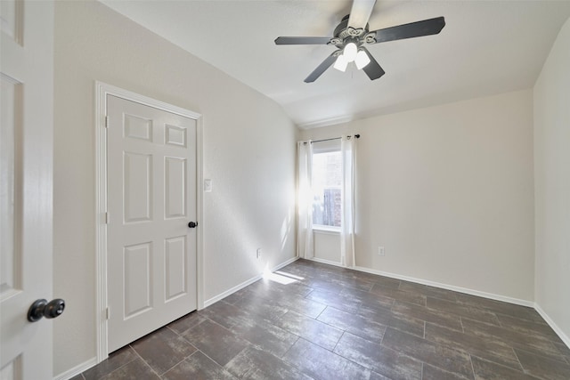 empty room featuring a ceiling fan, baseboards, and vaulted ceiling