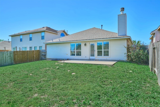 back of property with a yard, a patio area, a fenced backyard, and a chimney