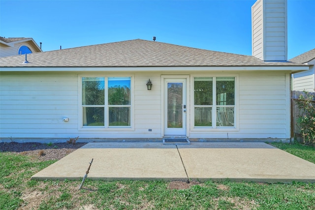 back of property featuring a chimney, a patio, and roof with shingles