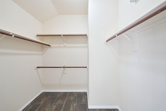 walk in closet with dark wood-style floors and vaulted ceiling