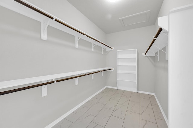 walk in closet featuring attic access and marble finish floor