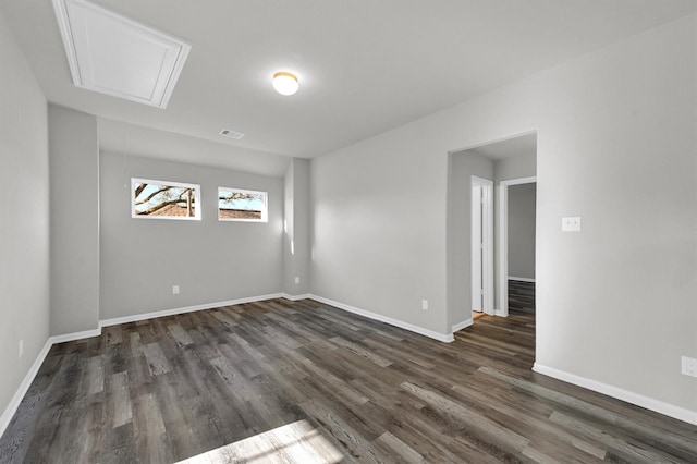 spare room with dark wood finished floors, attic access, visible vents, and baseboards