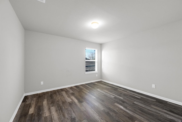 unfurnished room featuring baseboards and dark wood finished floors