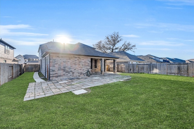 rear view of house with a lawn, a fenced backyard, brick siding, and a patio area