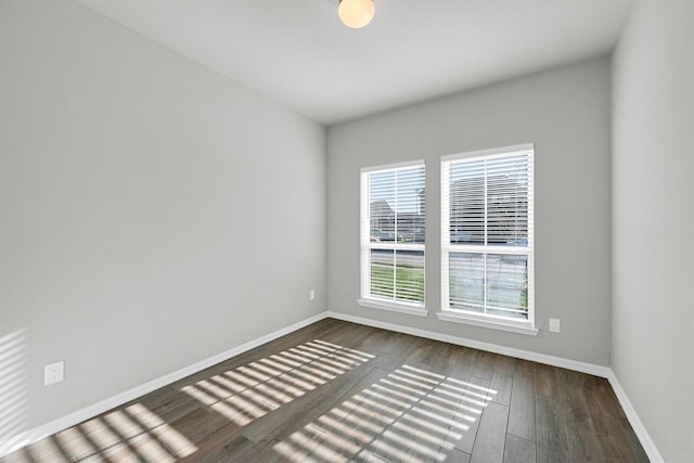 unfurnished room with dark wood-type flooring and baseboards