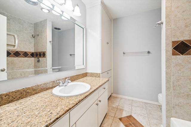 bathroom featuring tile patterned flooring, baseboards, toilet, tiled shower, and vanity