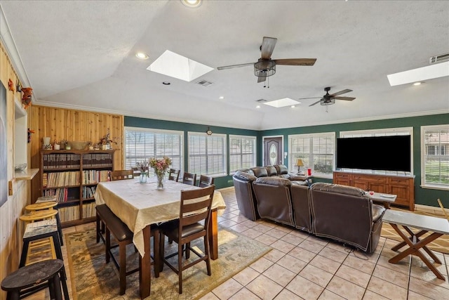 dining room with lofted ceiling with skylight, visible vents, light tile patterned floors, and ornamental molding