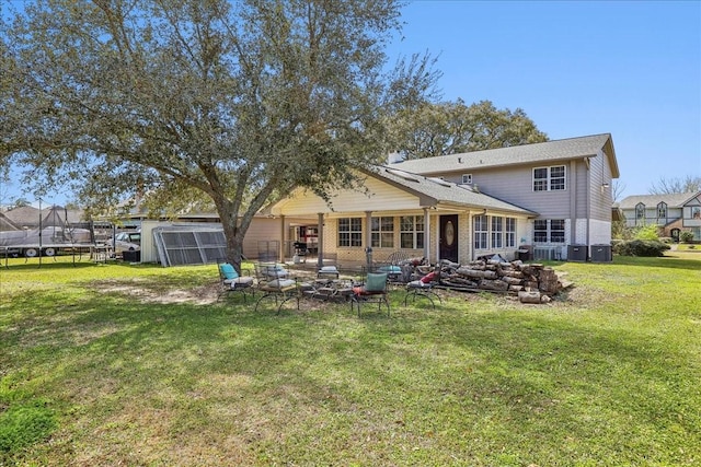 back of property with cooling unit, a trampoline, brick siding, and a lawn