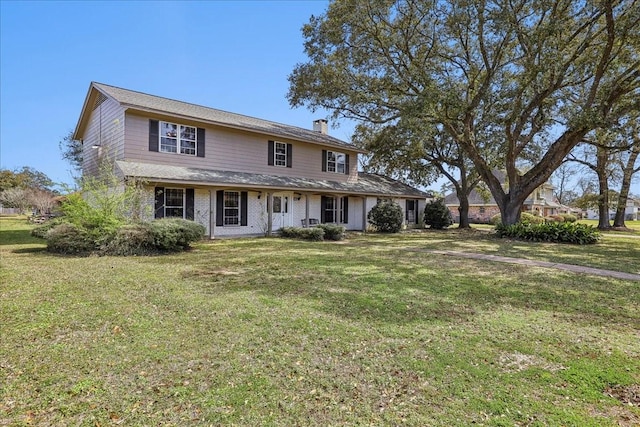 view of front of house with a front lawn, brick siding, and a chimney