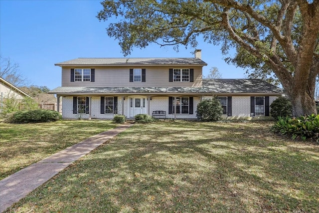 traditional-style home with brick siding, a chimney, and a front yard