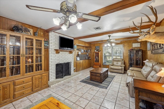 living area featuring wooden walls, visible vents, beamed ceiling, light tile patterned floors, and a fireplace