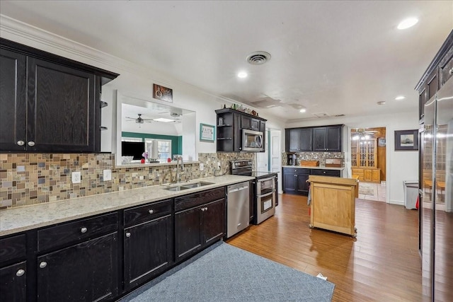 kitchen featuring visible vents, a sink, open shelves, wood finished floors, and appliances with stainless steel finishes