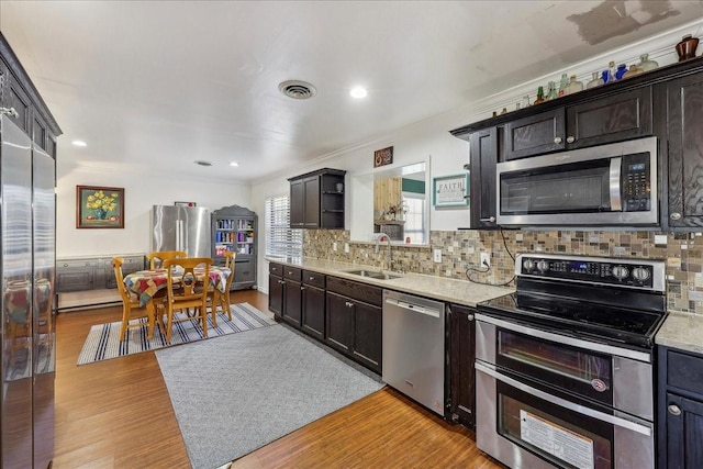 kitchen featuring visible vents, a sink, light wood-style floors, appliances with stainless steel finishes, and backsplash